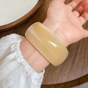Primo piano dettagliato della trama liscia di un ampio bracciale in acrilico ambra chiaro
