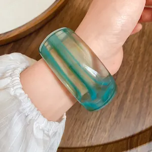 Vista dettagliata di un ampio bracciale in acrilico verde marmorizzato vintage al polso