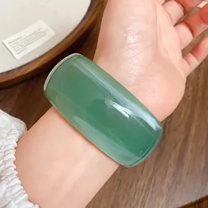 Primo piano dettagliato di un ampio bracciale rigido in acrilico verde traslucido sul polso