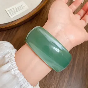 Dettaglio di un ampio bracciale in acrilico verde smeraldo con finitura lucida