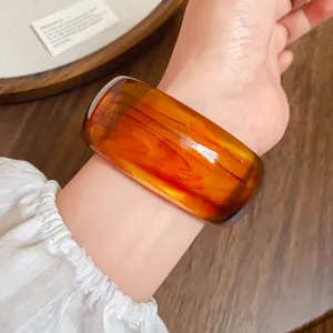 Dettaglio macro della trama marmorizzata ambra su questo bracciale rigido in acrilico.