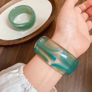 Vista dettagliata di un bracciale rigido largo in acrilico marmorizzato in stile vintage al polso