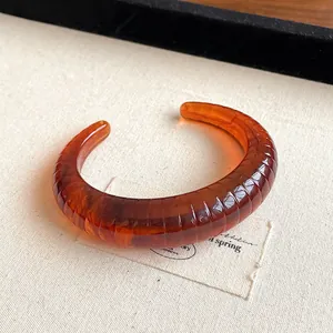 Stylish amber brown resin cuff bracelet featuring a ribbed texture and marbled pattern
