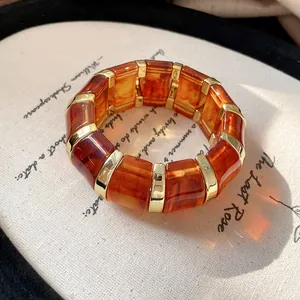 Amber marbled resin block bracelet with gold metal segments on vintage background.