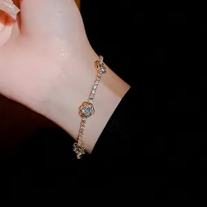 Élégant bracelet en or avec des breloques roses en zircone sur le poignet d'un modèle