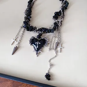 Macro detail of gothic style black crushed stone beaded necklace with silver cross heart