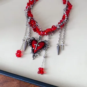Macro detail view of a gothic style red stone necklace with heart and cross pendants