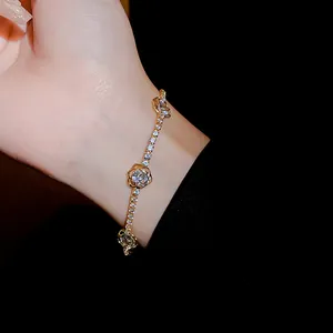 Détail d'un élégant bracelet fleur doré avec oxydes de zirconium porté au poignet.