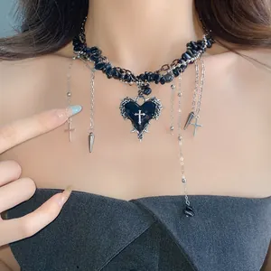 Close-up of a gothic heart cross necklace with irregular black stones on a model.