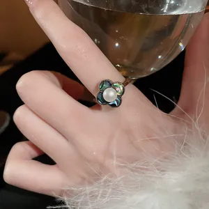 Gros plan d'une élégante bague fleur à quatre pétales dorée avec perle centrale