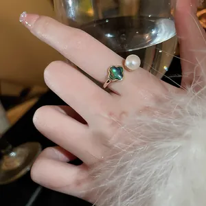 Gros plan élégant d'une bague fleur à quatre pétales et perle d'eau douce au doigt
