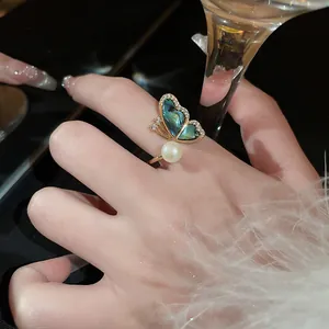 Détail macro d'une luxueuse bague papillon plaquée or avec une aile en abalone et une perle