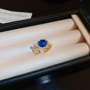 Gros plan d'une élégante bague plaquée or ornée d'une gemme bleue et de perles fines