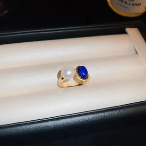 Gros plan élégant d'une bague plaquée or avec perle d'eau douce et pierre bleue.
