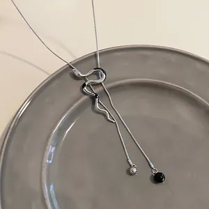 Modern silver-toned snake pendant necklace with a sleek snake chain shown on a gray plate