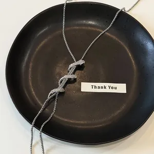 Close-up of sparkling rhinestone snake necklace on a textured black plate