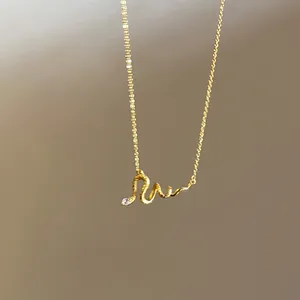 Detailed close-up of a delicate gold snake pendant necklace with zircon eyes.