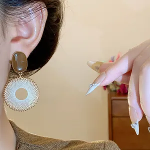 Close-up of retro ethnic mesh circular drop earrings worn on ear showing fine details