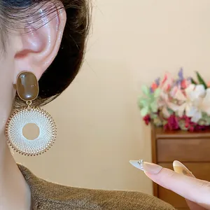 Detail shot of vintage style mesh circle earrings featuring a brown oval stone stud