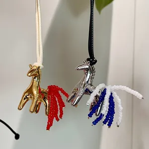 Detailed macro view of gold and silver horse pendants with elegant beaded tassels.