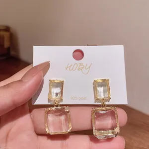 Close-up of transparent geometric square drop earrings with 925 silver post on card