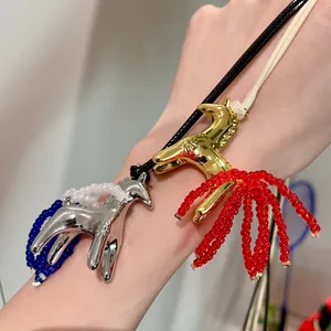 Close-up detail of two metallic horse necklaces with colorful beaded tassels on wax cords