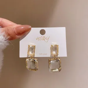 Close-up of elegant clear square drop earrings with 925 silver needle on white card