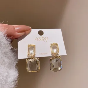 Close-up of transparent square crystal drop earrings with 925 silver post on white display card
