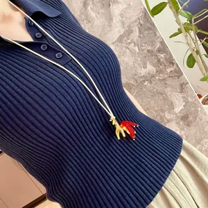 Detailed view of a vintage style golden horse pendant with red tassel on wax rope