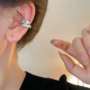 Primer plano de un ear cuff de serpiente plateado con circonitas en la oreja de la modelo