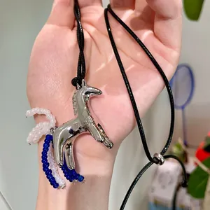 Close-up view of a silver horse pendant necklace with blue and white beaded fringe detail