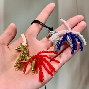 Detail of two horse-shaped tassel pendant necklaces with colorful beads on a hand.