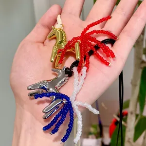 Close-up detail of stylish horse pendants with colorful bead tassels on a black wax cord