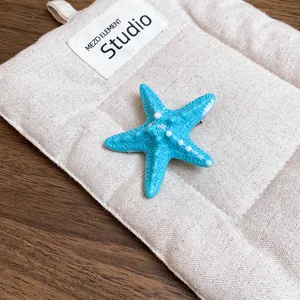 Detailansicht einer leuchtend blauen Seestern-Haarklammer für sommerliches Strandstyling.