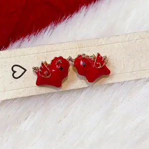 Red enamel horse earrings with gold wings presented on a luxury white fur background