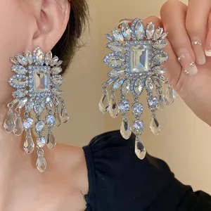 Close-up of oversized silver needle earrings with square rhinestones and crystal tassels
