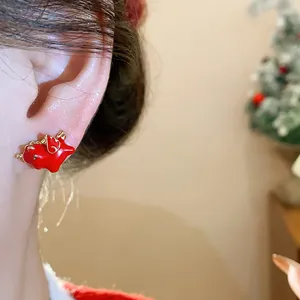 Close-up of red enamel horse stud earring worn on ear with silver needle.