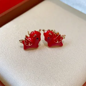 Macro view of red enamel winged horse stud earrings with gold-toned details and silver needles