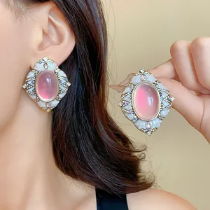 Primo piano di orecchini vintage con pietra rosa, cornice bianca e strass brillanti