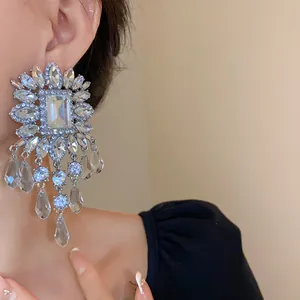 Close-up of oversized silver tassel earrings with sparkling square glass stones