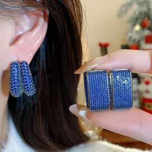 Close-up of blue zircon encrusted geometric hoop earrings with a sparkling finish.