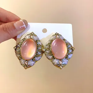Dettaglio di orecchini vintage rosa con montatura dorata e strass scintillanti
