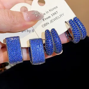 Close-up of blue zircon geometric hoop earrings showing sparkling details and texture.