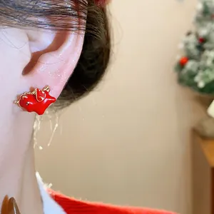 Detail shot of a festive red enamel winged horse stud earring worn on a model's ear