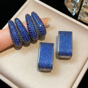 Macro view of blue zircon paved geometric hoop earrings with a shiny silver finish.
