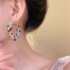 Primo piano di orecchini a cerchio con perle e perline di vetro colorate su orecchio.