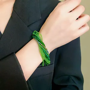 Close-up of a multi-layer green beaded bracelet with crystals on a woman's wrist.