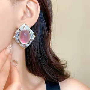 Orecchino vintage di lusso con pietra rosa ovale e dettaglio della cornice bianca vista