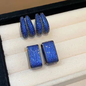 Close-up of sparkling blue zircon pavé geometric hoop earrings in a jewelry tray.