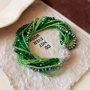 Close-up detail of multi-layer green crystal beaded bracelet with rhinestone clasp.